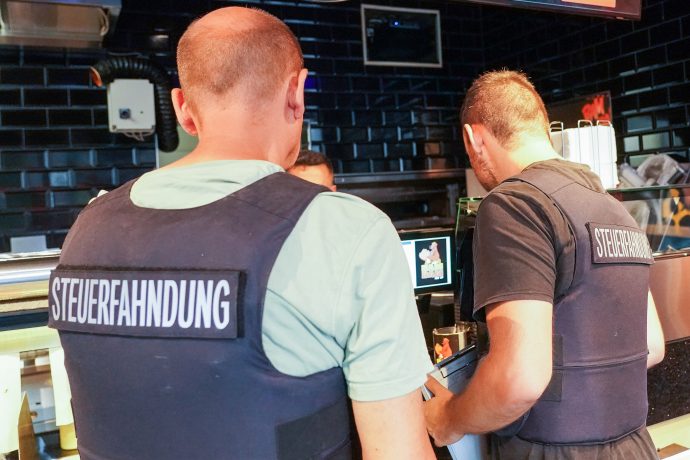 Zwei Männer der Steuerfahndung in einem Geschäft.