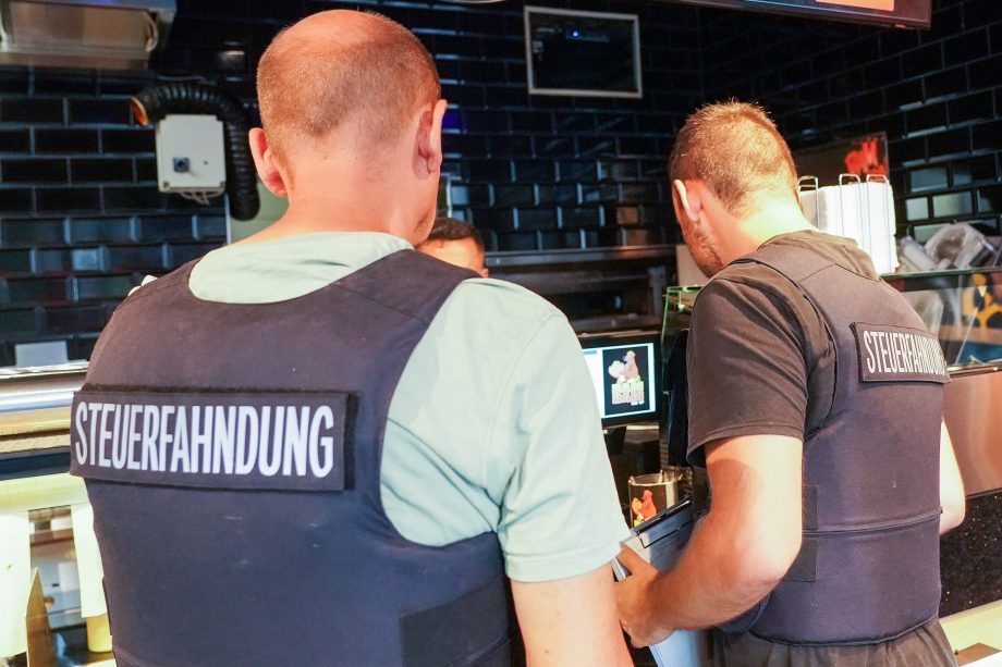 Zwei Männer der Steuerfahndung in einem Geschäft.