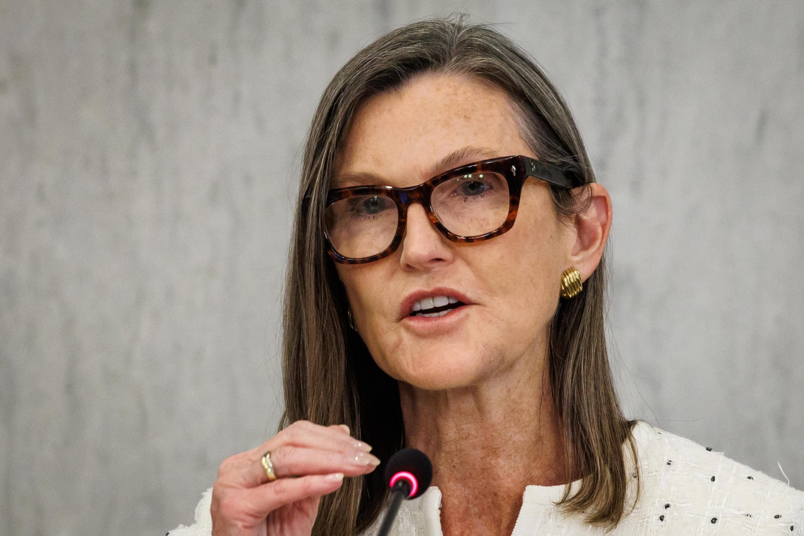 Eine Frau mit Brille und feiner Bluse vor einem Mikrofon.