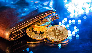 Eine Bitcoin Wallet liegt auf dem Tisch und die Münzen fallen heraus.