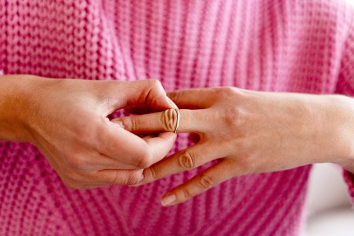 Eine Frau nimmt ihren Ring vom Finger und trägt einen pinken Pullover. Was passiert mit Bitcoin?