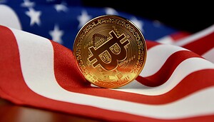 Eine goldene Bitcoin-Münze ruht aufrecht auf einer amerikanischen Flagge und symbolisiert Krypto und Kryptowährungen in den Vereinigten Staaten.