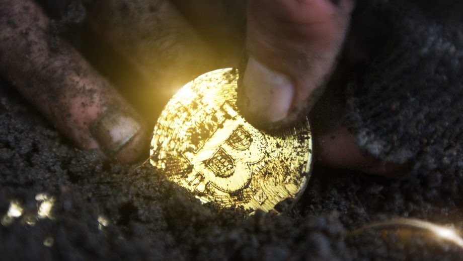 Bitcoin-Münze in der Erde