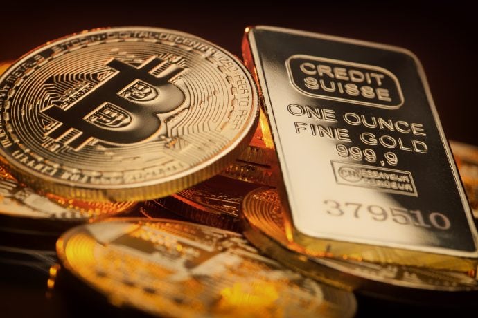 Eine Bitcoin-Münze neben einem Goldbarren