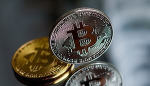 Eine aufrecht stehende Bitcoin-Münze vor einem verspiegelten Hintergrund