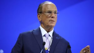 Ein Mann im schwarzem Anzug hinter einem Rednerpult