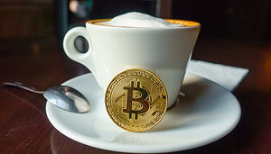Eine Bitcoin-Münze angelehnt an eine Kaffee-Tasse