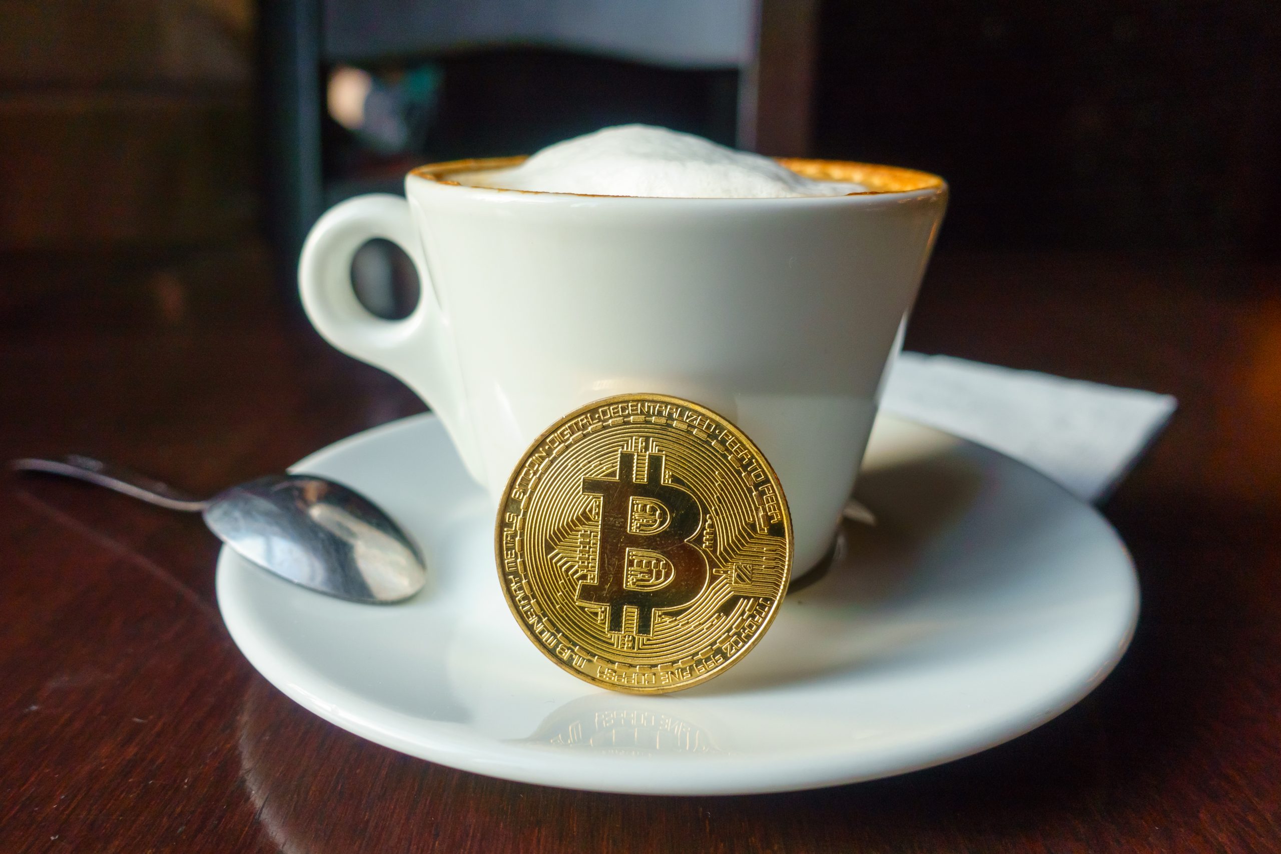 Eine Bitcoin-Münze angelehnt an eine Kaffee-Tasse