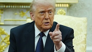 Donald Trump sitzt im Oval Office und hebt den linken Zeigefinger.