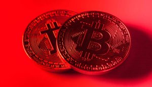 Zwei physische Bitcoin-Token (BTC) werden unter rotem Licht gezeigt, wobei auf ihrer Oberfläche kreislaufähnliche Muster zu erkennen sind, die das digitale Wesen von Bitcoin hervorheben.