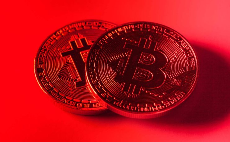Droht Bitcoin ein roter März? Zwei physische Bitcoin-Token (BTC) werden unter rotem Licht gezeigt, wobei auf ihrer Oberfläche kreislaufähnliche Muster zu erkennen sind, die das digitale Wesen von Bitcoin hervorheben.