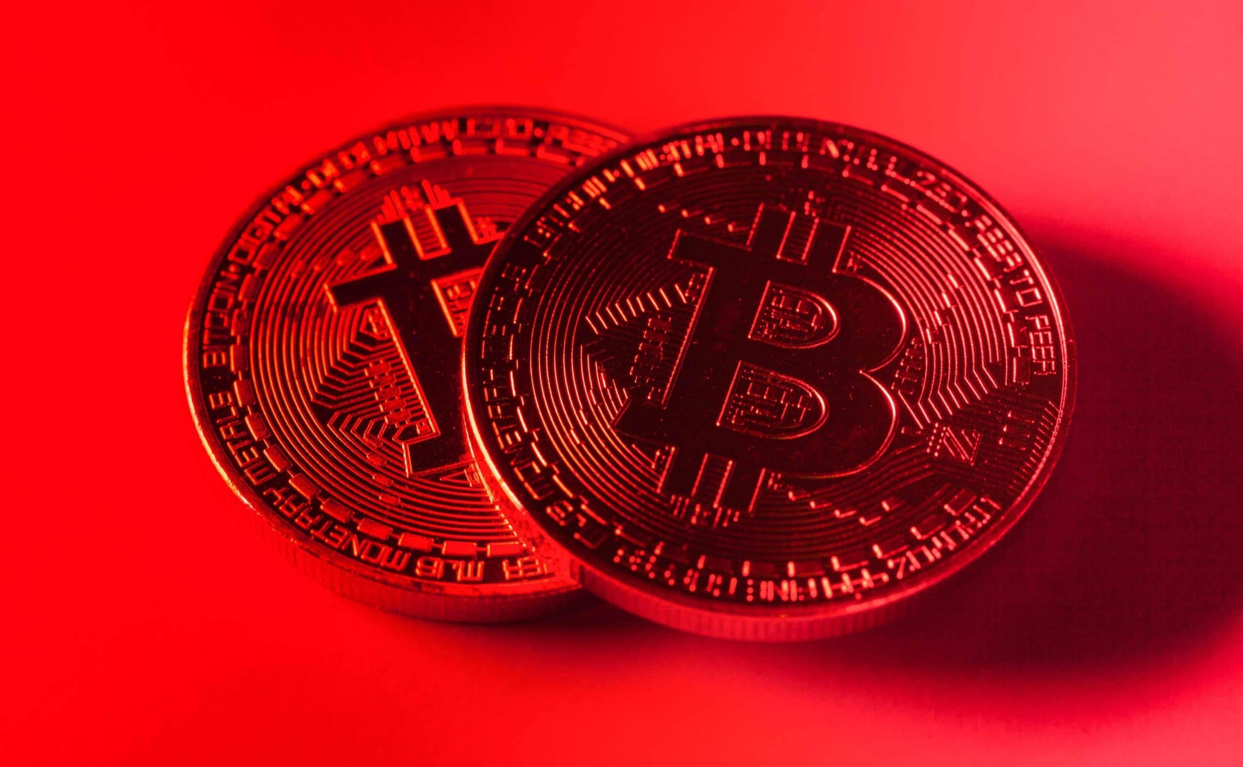 Zwei physische Bitcoin-Token (BTC) werden unter rotem Licht gezeigt, wobei auf ihrer Oberfläche kreislaufähnliche Muster zu erkennen sind, die das digitale Wesen von Bitcoin hervorheben.