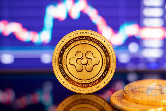 Das Bild zeigt eine goldene Kryptowährungs-Münze im Mittelpunkt, scharf fokussiert und leicht frontal ausgerichtet. I