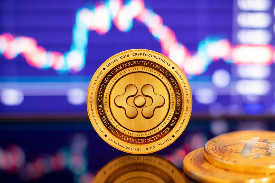 Das Bild zeigt eine goldene Kryptowährungs-Münze im Mittelpunkt, scharf fokussiert und leicht frontal ausgerichtet. I