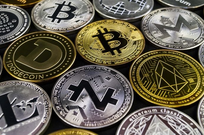 Eine Nahaufnahme verschiedener physischer Münzen, die verschiedene Kryptowährungen repräsentieren, darunter Bitcoin, Dogecoin und Litecoin.