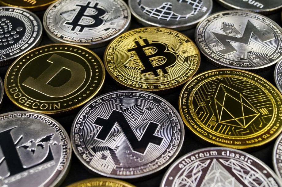 Eine Nahaufnahme verschiedener physischer Münzen, die verschiedene Kryptowährungen repräsentieren, darunter Bitcoin, Dogecoin und Litecoin.
