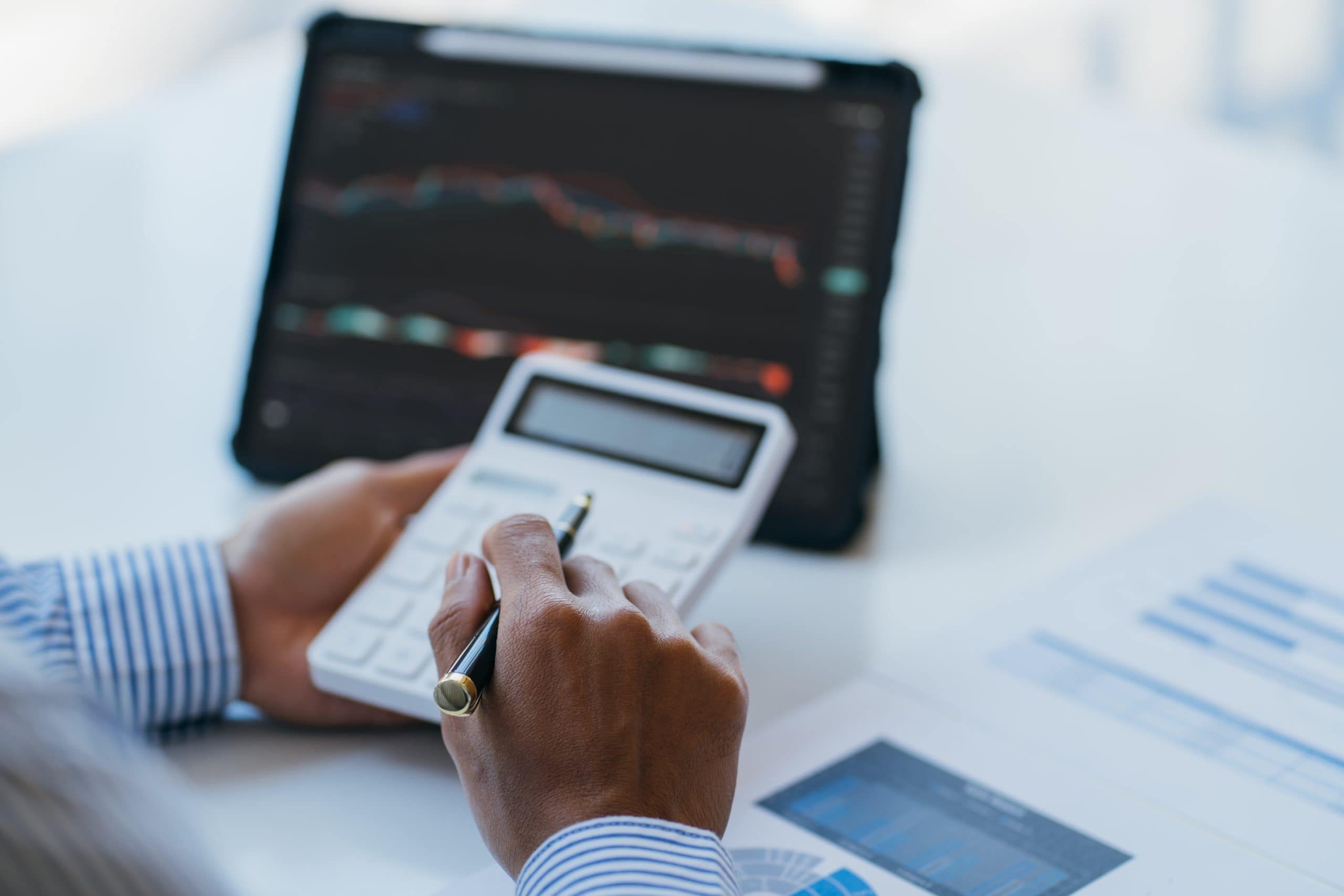 Eine Person, die vor einem Laptop sitzt, hält einen Taschenrechner