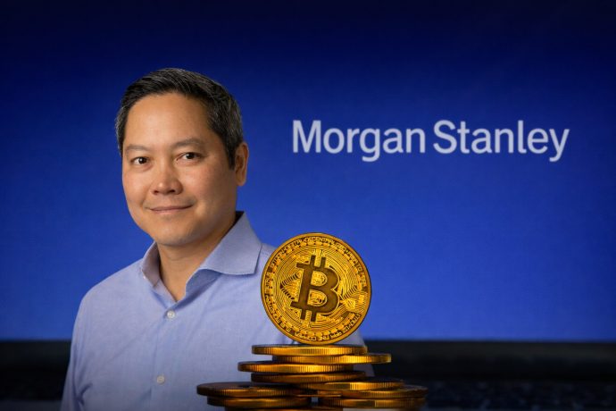 Ein professionell wirkender Mann in einem hellblauen Hemd steht auf der linken Seite des Bildes und ist etwas kleiner dargestellt, mit einem ruhigen Lächeln. Im Vordergrund rechts befindet sich ein Stapel glänzender goldener Bitcoin-Münzen. Im Hintergrund ist ein blauer Farbverlauf zu sehen, auf dem das weiße „Morgan Stanley“-Logo klar erkennbar, aber leicht unscharf dargestellt ist – eine saubere, finanzbezogene Bildkomposition.
