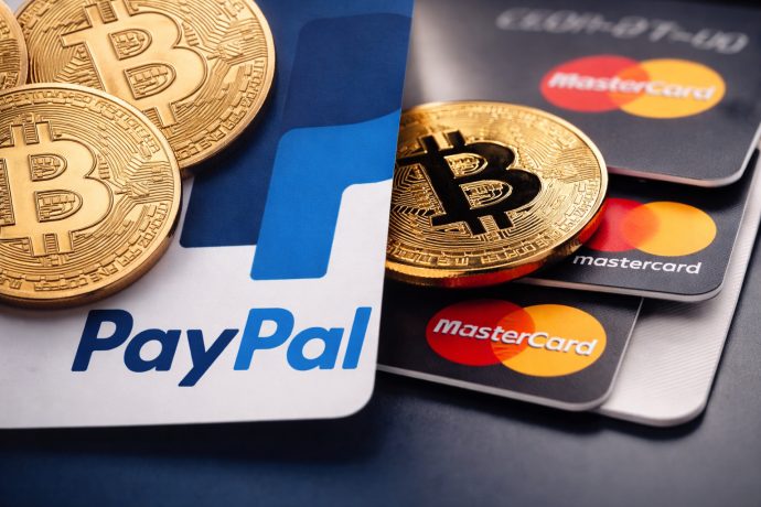 Dieses Bild zeigt das Paypal-Logo und eine Mastercard-Karte, mit Bitcoin-Münzen geschmückt. Es soll die Stablecoin-Adoption veranschaulichen.