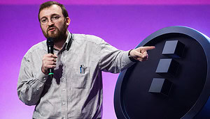 Charles Hoskinson zeigt während einer Präsentation auf einen großen Kryptowährungs-Token Midnight.