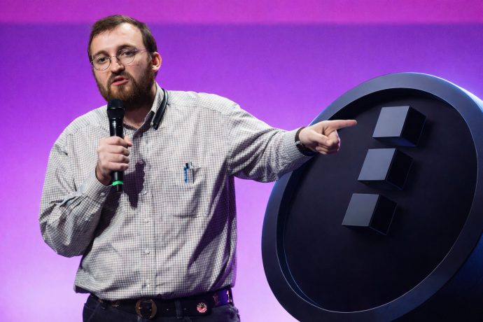 Charles Hoskinson zeigt während einer Präsentation auf einen großen Kryptowährungs-Token Midnight.