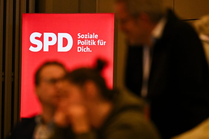 Eine unscharfe Menschengruppe unterhält sich vor dem SPD-Parteilogo.