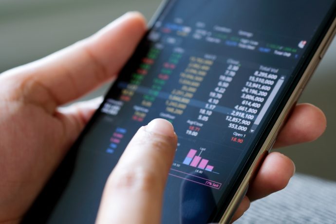 Eine Hand hält ein Smartphone, auf dem mehrere Kurse abgebildet sind