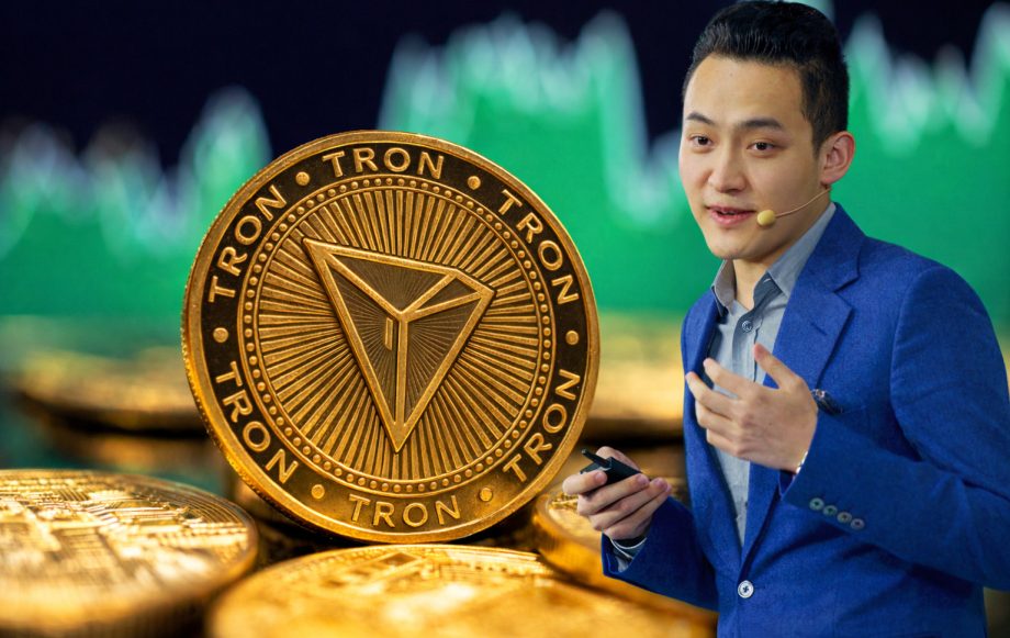 Tron-Gründer Justin Sun vor einer großen TRX-Münze mit Kursgrafik im Hintergrund.