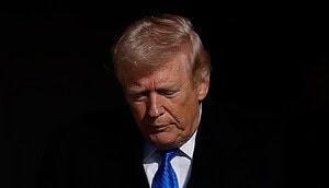 Donald Trump vor schwarzem Hintergrund mit blauer Krawatte.