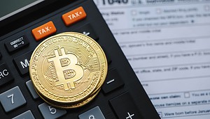 Eine Bitcoin-Münze liegt auf einem Taschenrechner