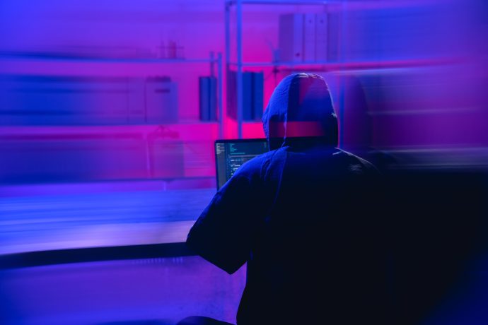 Ein Hacker vor einem lila Hintergrund