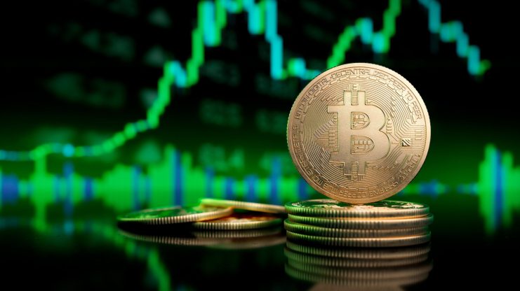 Eine Bitcoin-Münze vor einem grünen Chartdiagramm.