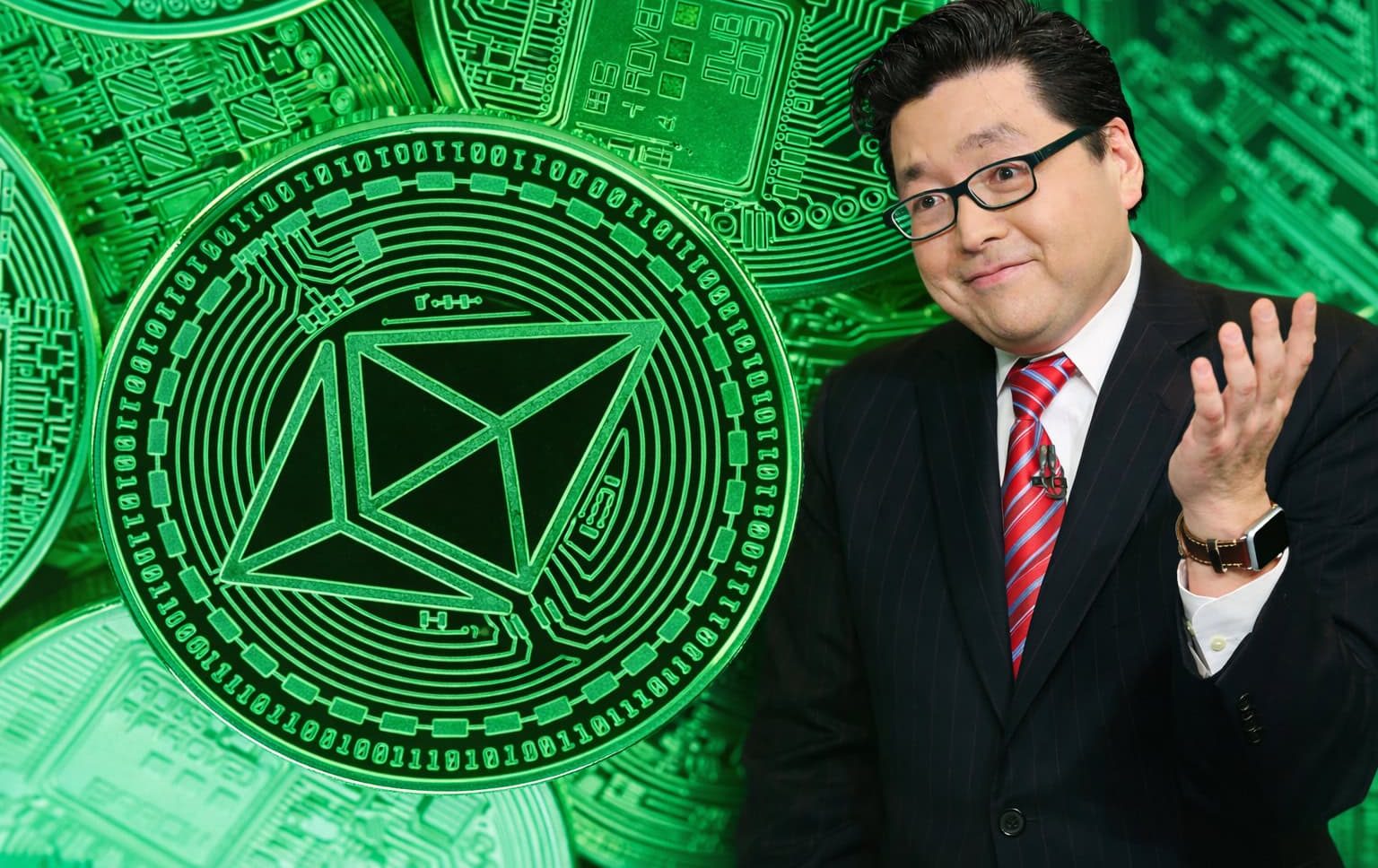 Ein Mann im Anzug mit roter Krawatte und Brille steht rechts im Bild und gestikuliert mit einer Hand, während im Hintergrund große, grün leuchtende Ethereum-Münzen mit technischen Mustern zu sehen sind.