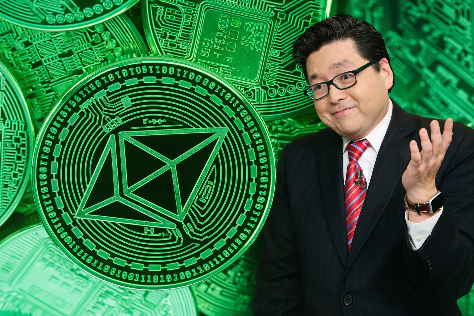Ein Mann im Anzug mit roter Krawatte und Brille steht rechts im Bild und gestikuliert mit einer Hand, während im Hintergrund große, grün leuchtende Ethereum-Münzen mit technischen Mustern zu sehen sind.