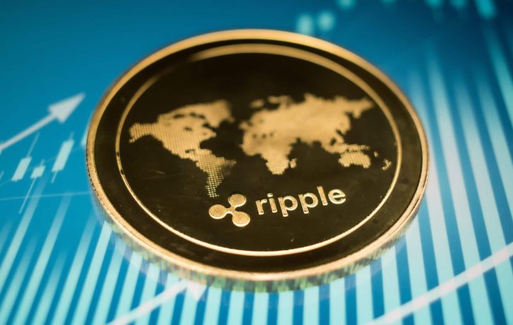 Eine Nahaufnahme einer XRP-Münze mit einem Weltkartenmotiv auf blauem Hintergrund mit Finanzgrafikelementen.