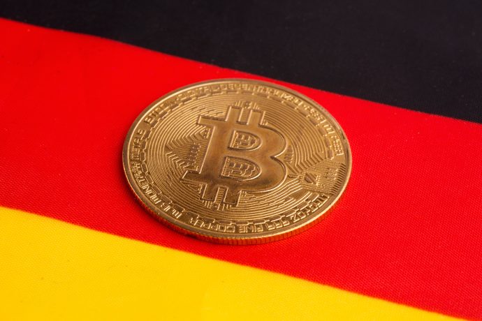 Das Bild zeigt eine Bitcoin-Münze auf einer Deutschland Flagge