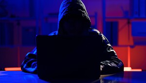 Das Bild zeigt eine Hacker vor einem Laptop