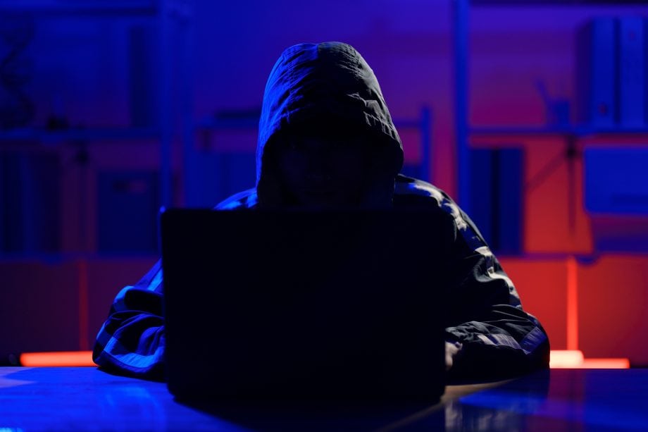 Das Bild zeigt eine Hacker vor einem Laptop