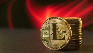 Das Bild zeigt die Litecoin-Münze vor einem roten Hintergrund.