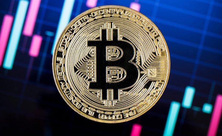 Steht dem Bitcoin-Kurs ein Sturm bevor? Eine Bitcoin-Münze vor einem Kurschart.