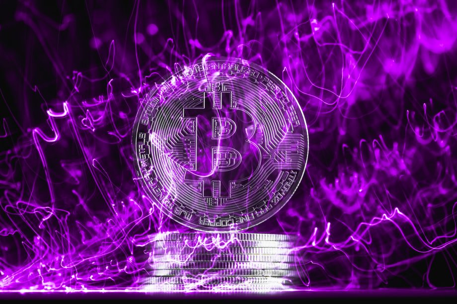 Eine Bitcoin-Münze vor lila Hintergrund