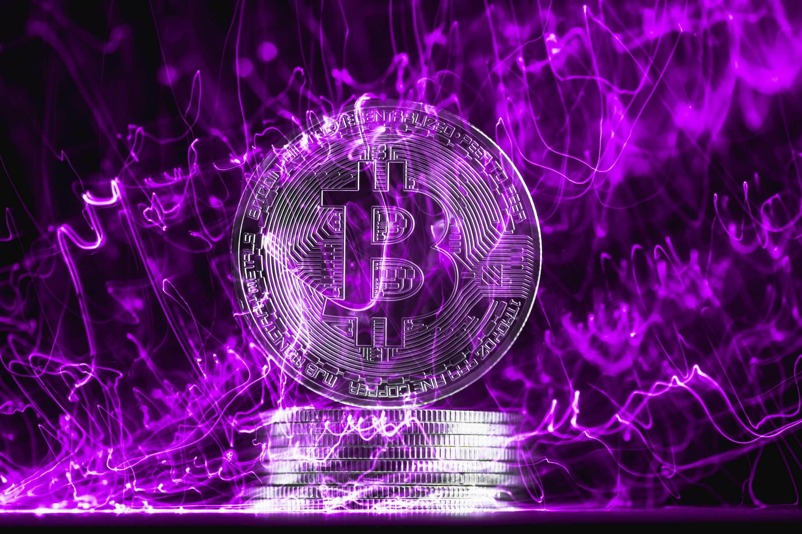 Eine Bitcoin-Münze vor lila Hintergrund