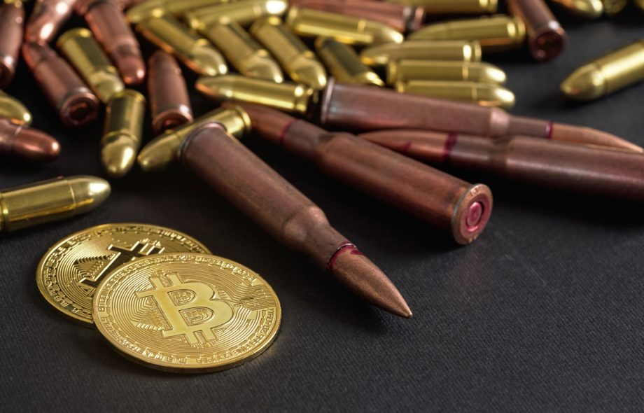 Das Bild zeigt eine Bitcoin-Münze vor Patronen