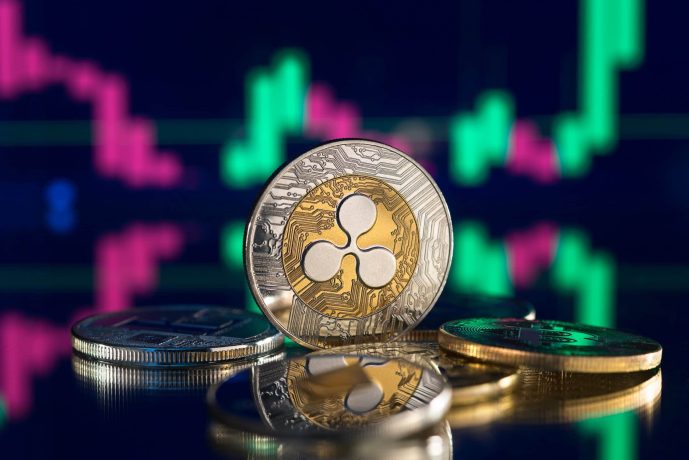 Eine Nahaufnahme von Ripple (XRP)-Kryptowährungsmünzen auf einer spiegelnden Oberfläche mit einem digitalen Preisdiagramm, das den XRP-Kursverlauf zeigt.