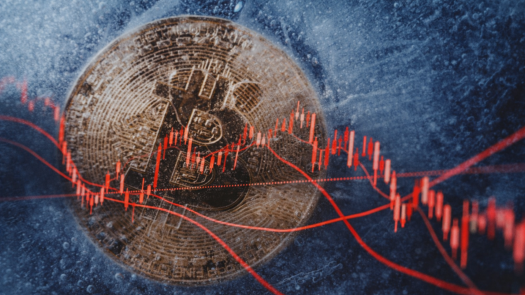 Eine eingefrorene Bitcoin-Münze vor einem fallenden Chart