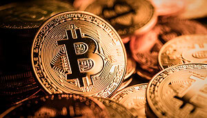 Mehrere goldenfarbene Bitcoin-Münzen sind übereinander gestapelt.