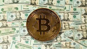 Eine Bitcoin-Münze liegt auf vielen Dollarscheinen