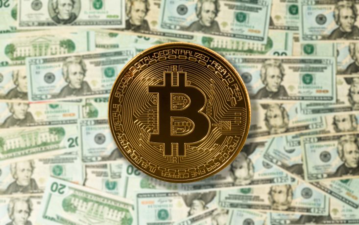 Eine Bitcoin-Münze liegt auf vielen Dollarscheinen