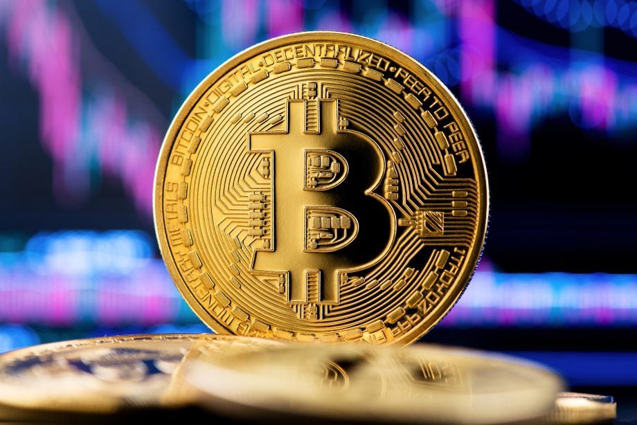 Eine Bitcoin-Münze vor einem lila Hintergrund