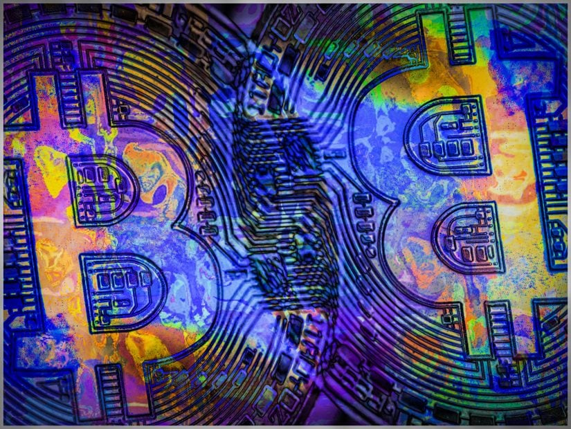 Zwei Bitcoin-Münzen werden von einem bläulichen Licht angestrahlt.